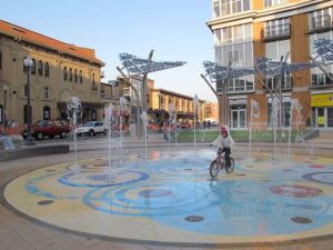 A child rides a bike through a spray-ground water park in Columbia Heights