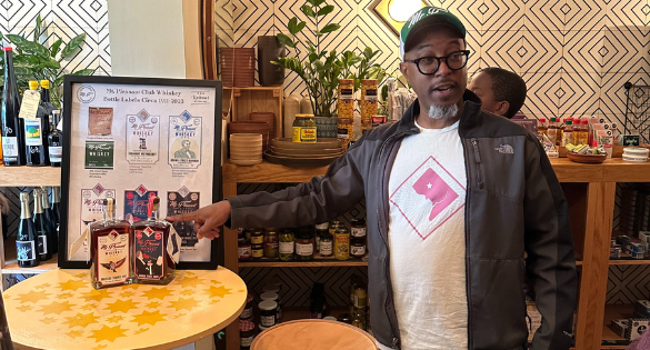 A man standing next to a table containing samples of whiskey